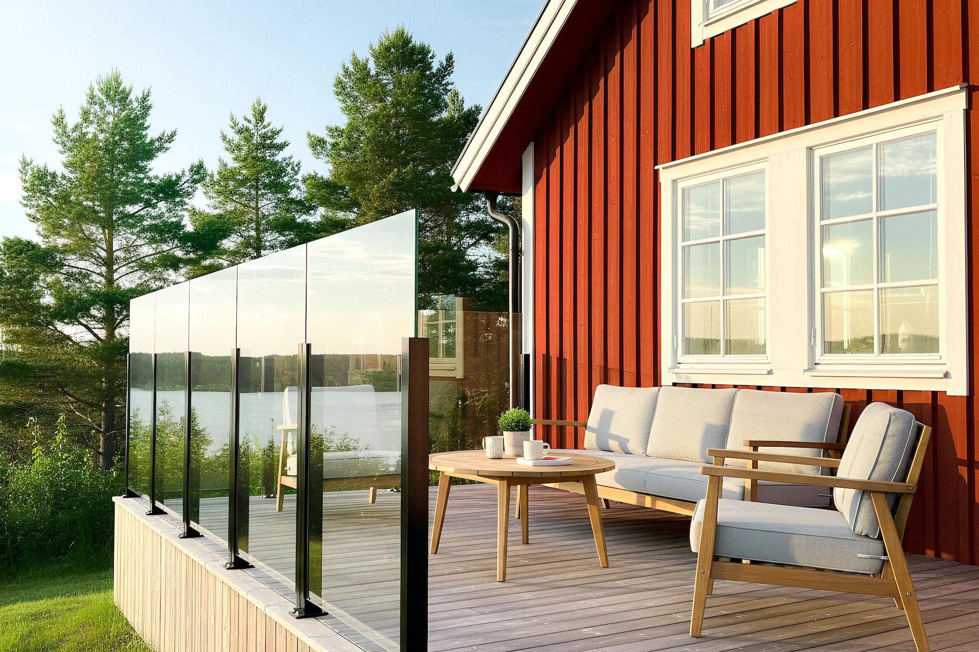 Lasinen tuulisuojakaide omakotitalon terassilla järvimaisemassa