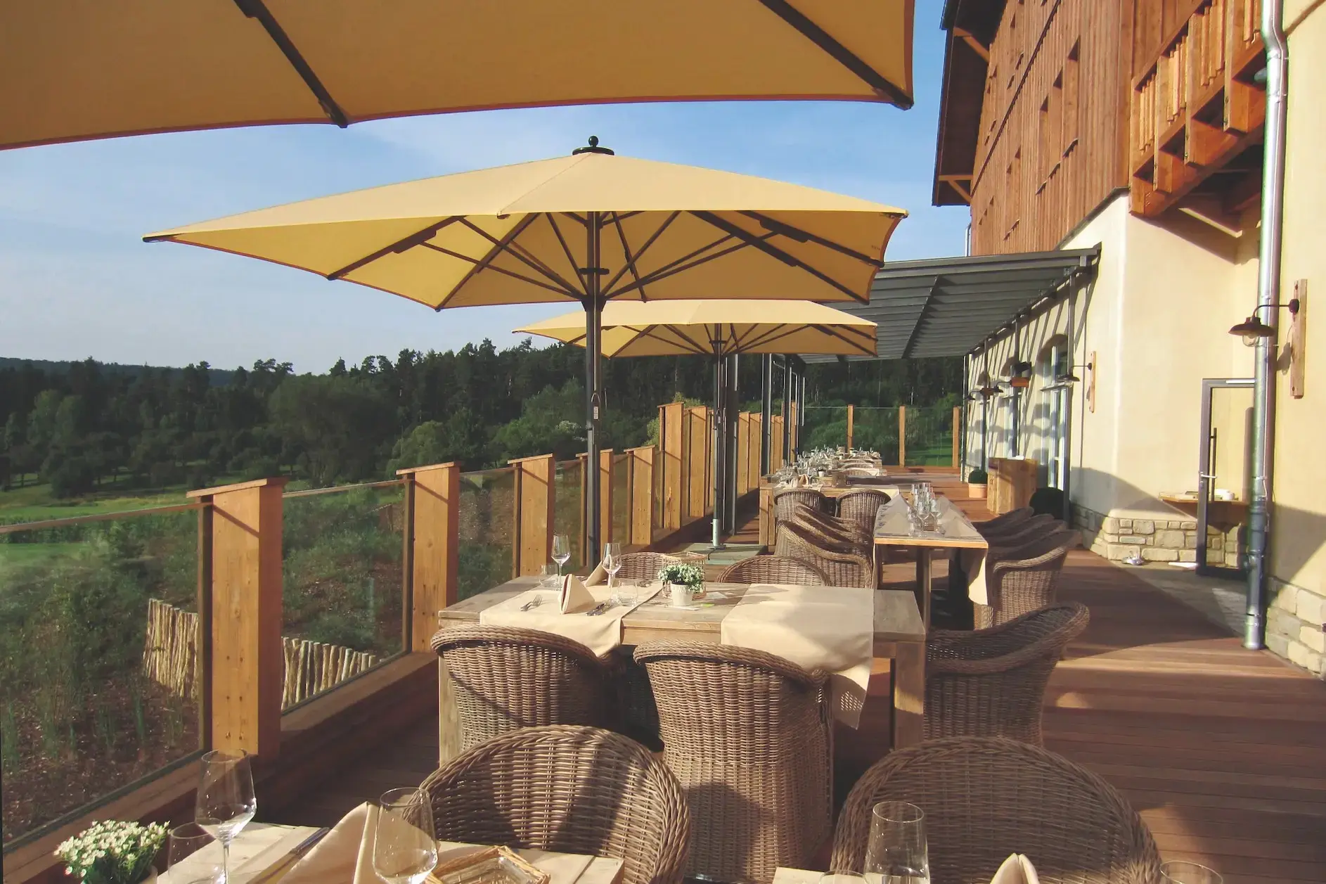 Kaksi Jumbrella-varjoa aurinkoisella hotellipihalla, vuoristotausta