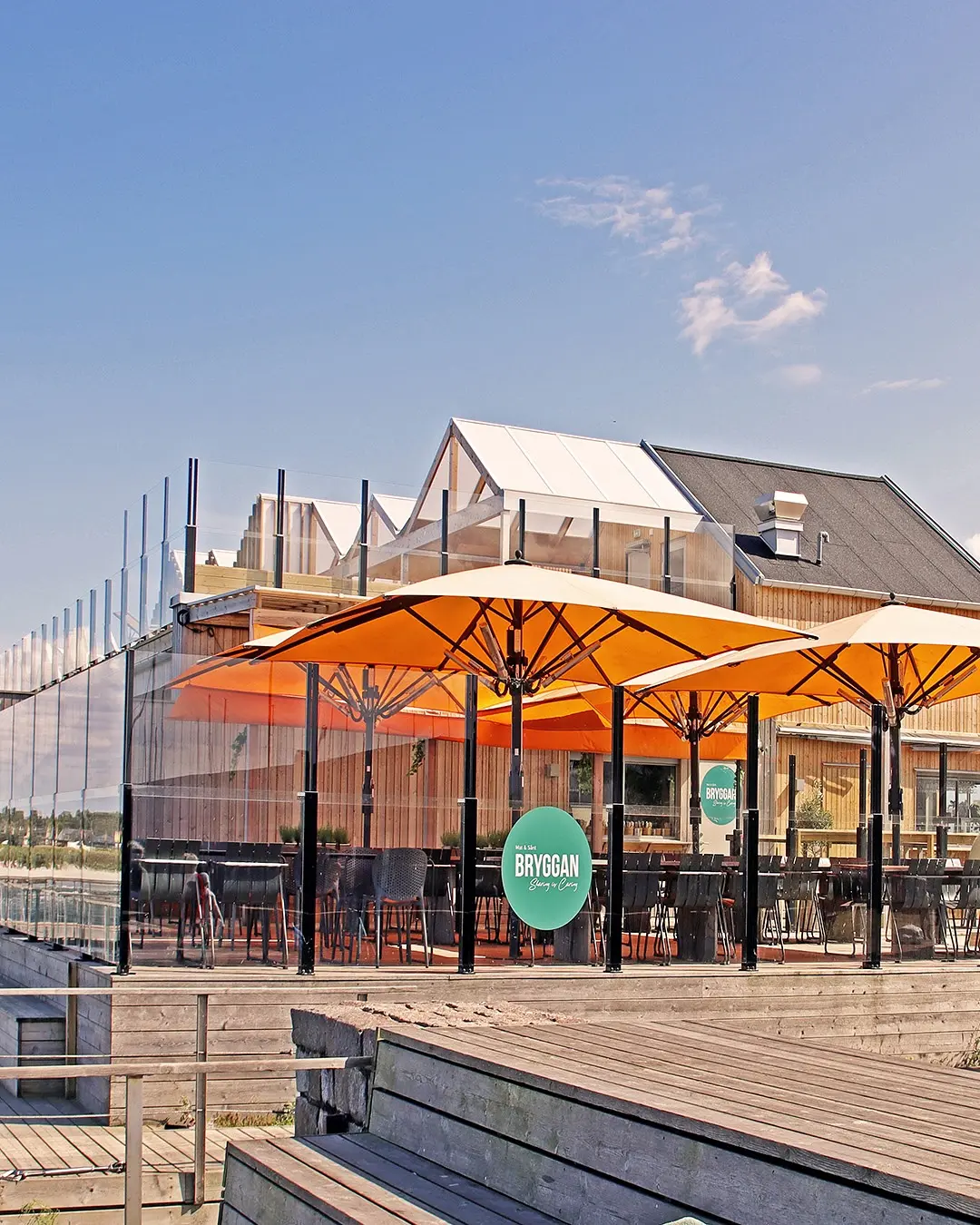 Moderni kahvilaterassi oransseilla Bahama-aurinkovarjoilla ja ClickitUp-laseilla