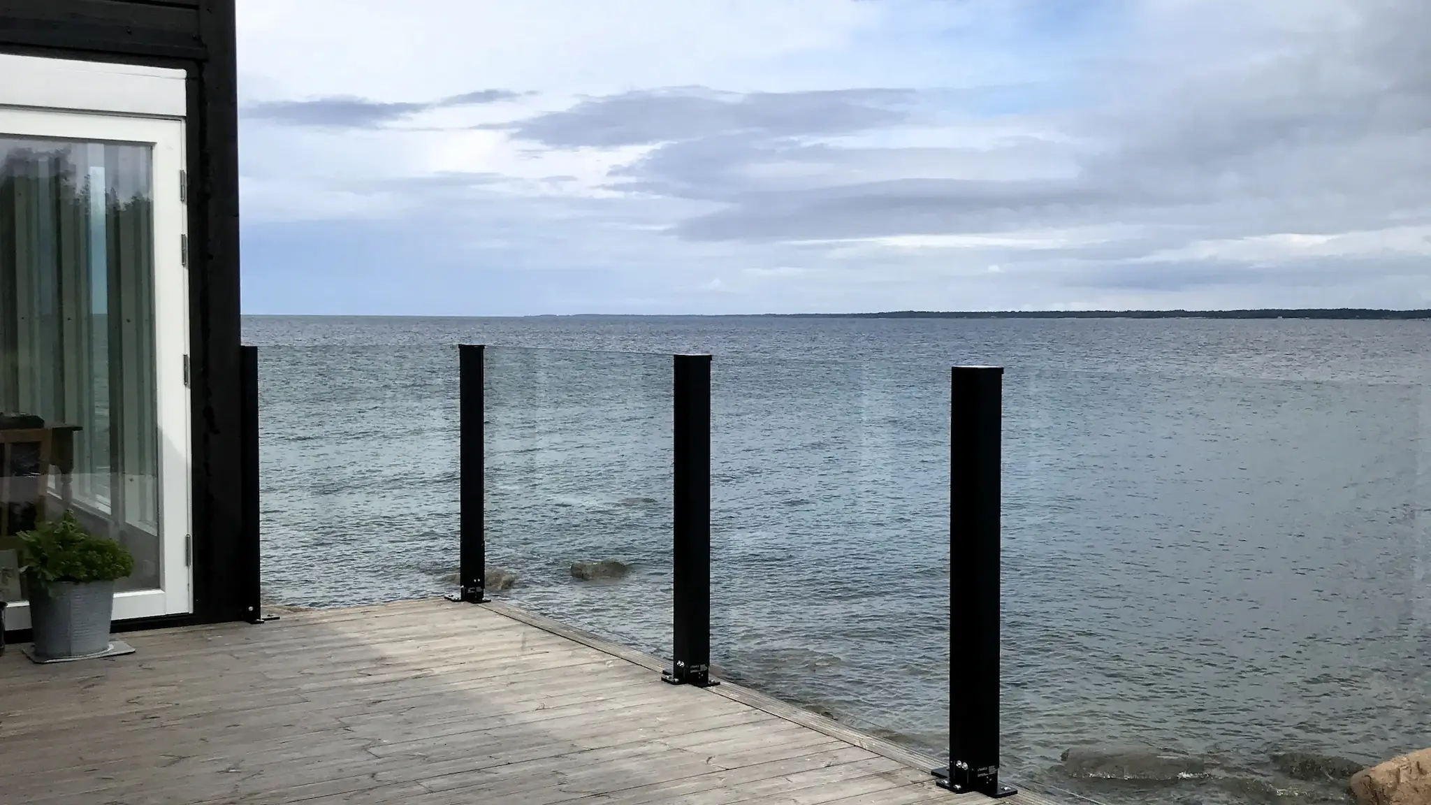 Kiinteä lasikaide meren rannassa – suora muotoilu ja suojaus aallonmurtajalla.