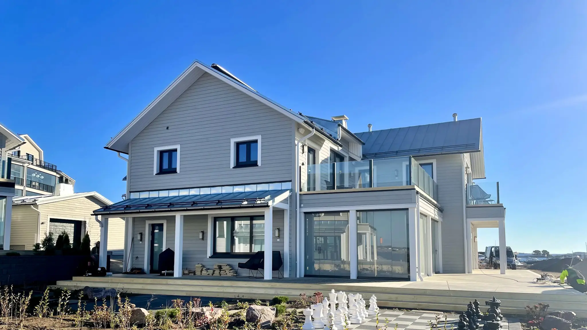 Kiinteä lasikaide modernin talon parvekkeella – vaalea talo ja selkeä rakenne.