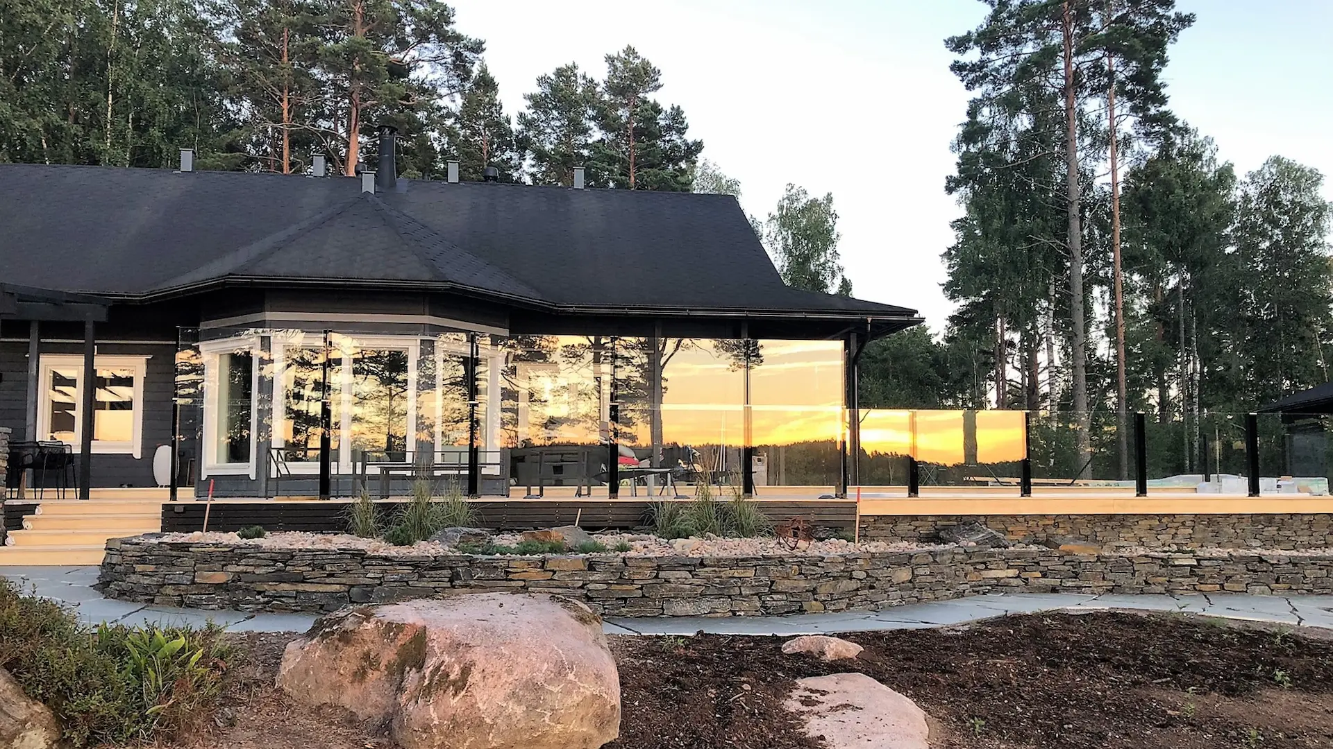 Nostettavat lasikaiteet mökkikohteen terassilla luonnon keskellä.